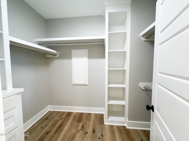 walk in closet with light wood finished floors