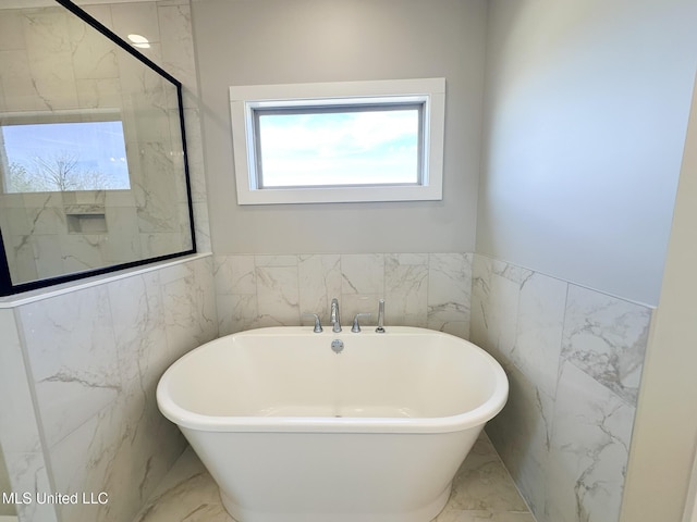 full bath with a freestanding tub, wainscoting, and marble finish floor