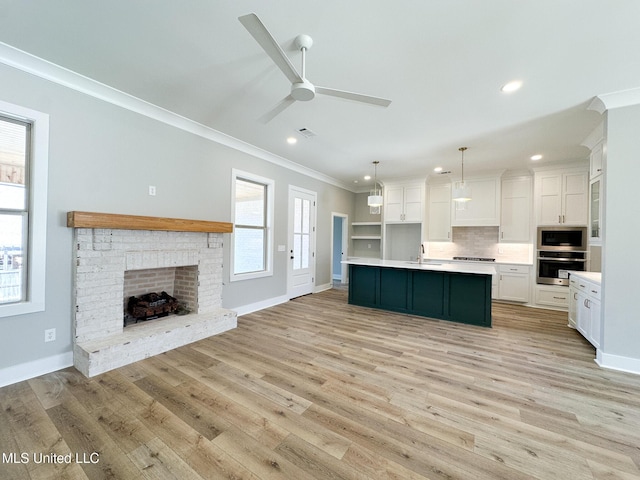 kitchen with white cabinets, open floor plan, light countertops, appliances with stainless steel finishes, and decorative light fixtures