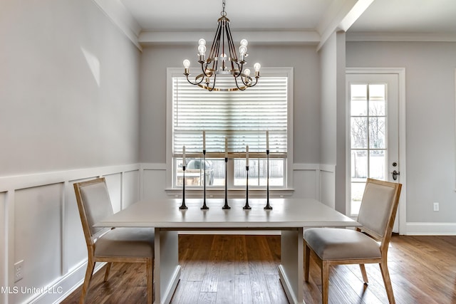 dining room featuring hardwood / wood-style flooring, a decorative wall, crown molding, and an inviting chandelier