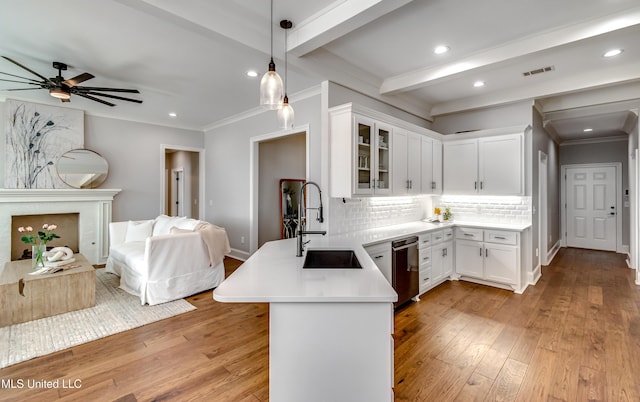 kitchen with a peninsula, light wood-style flooring, backsplash, and a sink