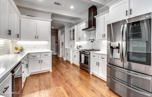 kitchen with stainless steel appliances, light countertops, visible vents, white cabinets, and wall chimney range hood