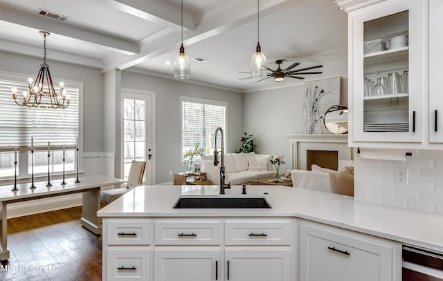 kitchen featuring light countertops, visible vents, dark wood-type flooring, a sink, and beamed ceiling