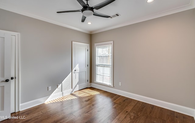 spare room with baseboards, visible vents, ceiling fan, ornamental molding, and wood finished floors