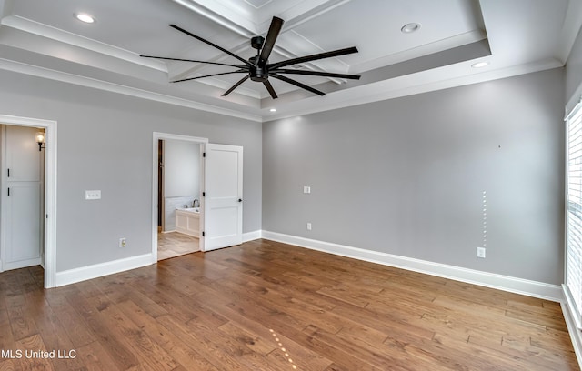 unfurnished bedroom with a tray ceiling, hardwood / wood-style floors, and baseboards