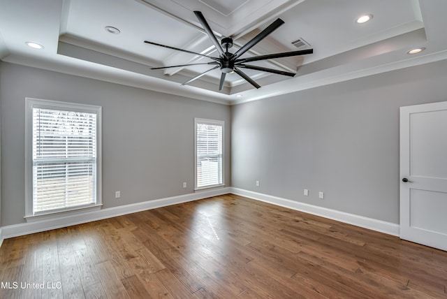 unfurnished room with a tray ceiling, hardwood / wood-style flooring, visible vents, and baseboards