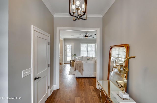 hallway featuring crown molding, baseboards, and wood finished floors