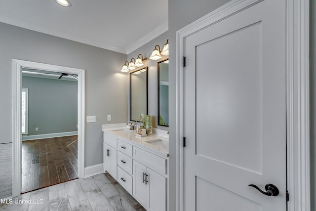 full bath featuring a sink, double vanity, wood finished floors, and baseboards