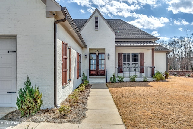 view of front of property with french doors, brick siding, a shingled roof, a standing seam roof, and metal roof