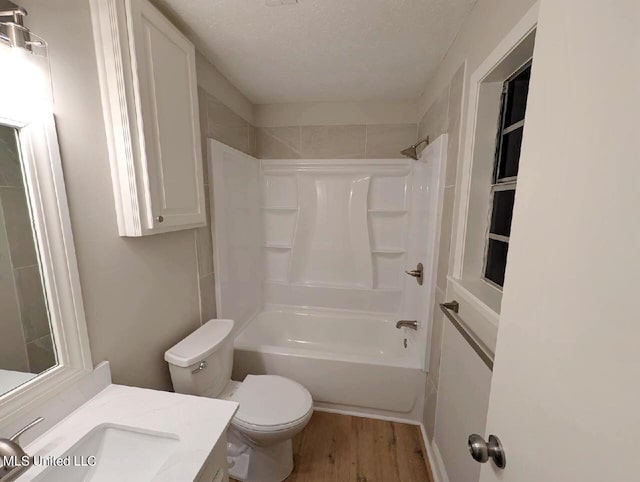 full bathroom featuring wood-type flooring, bathing tub / shower combination, a textured ceiling, toilet, and vanity