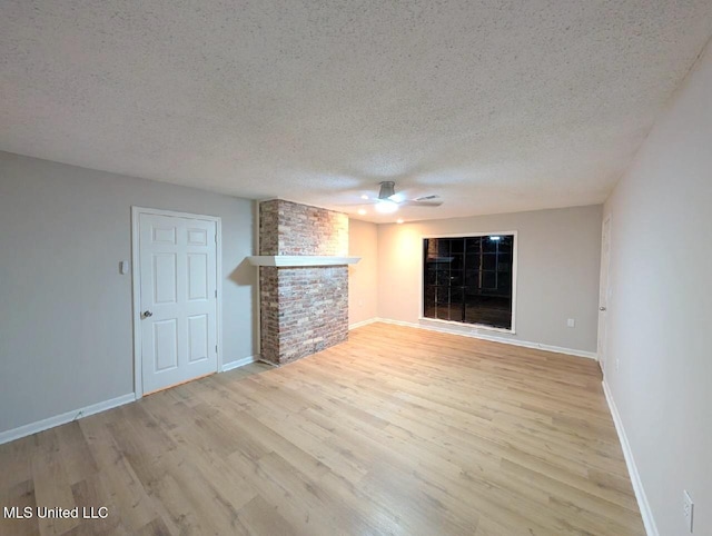 unfurnished living room featuring a brick fireplace, a textured ceiling, light wood-type flooring, and ceiling fan