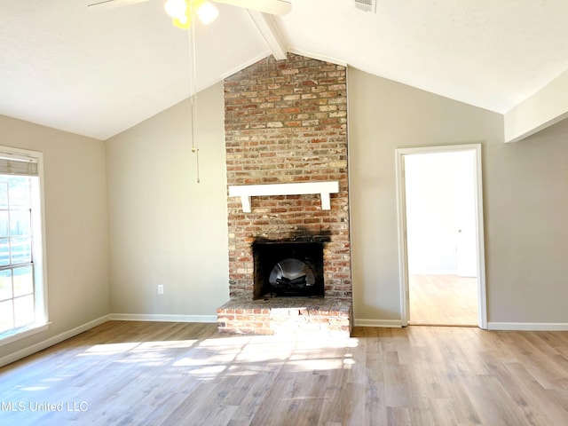 unfurnished living room with light hardwood / wood-style floors, vaulted ceiling with beams, a fireplace, and ceiling fan