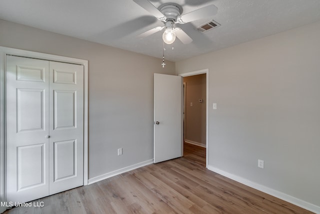 unfurnished bedroom with light hardwood / wood-style flooring, a closet, and ceiling fan