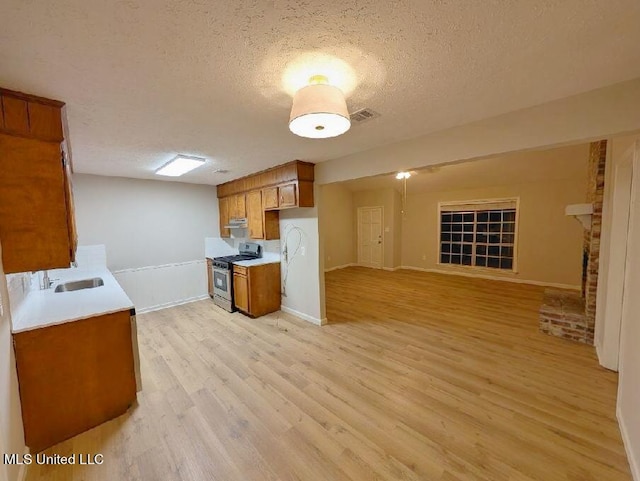 kitchen featuring sink, a textured ceiling, gas stove, and light wood-type flooring