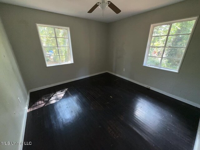 unfurnished room featuring ceiling fan, plenty of natural light, and dark hardwood / wood-style flooring