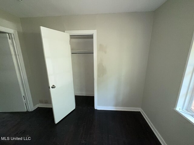 unfurnished bedroom featuring a closet and dark hardwood / wood-style flooring