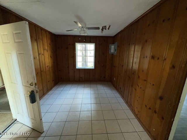 unfurnished room featuring crown molding, wood walls, light tile patterned flooring, and ceiling fan