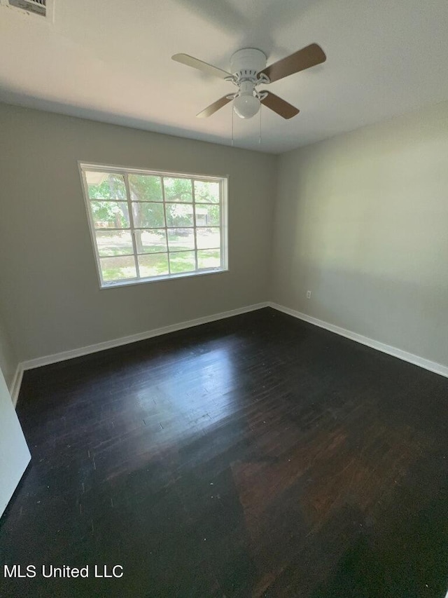 empty room featuring dark wood-type flooring and ceiling fan