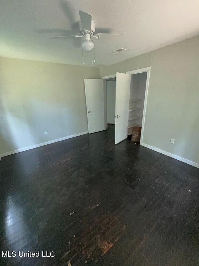 empty room with dark wood-type flooring and ceiling fan