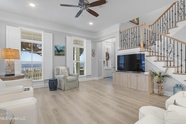 living room featuring ceiling fan, visible vents, ornamental molding, stairway, and light wood-type flooring