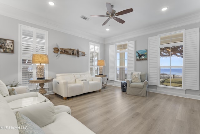 living room with light wood-type flooring, recessed lighting, visible vents, and ornamental molding