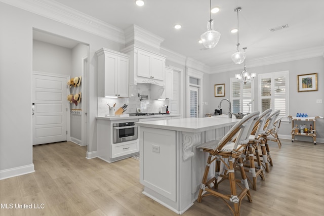 kitchen with crown molding, tasteful backsplash, light countertops, white cabinets, and oven