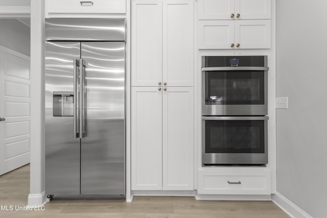 kitchen with appliances with stainless steel finishes, white cabinetry, and light wood-style flooring