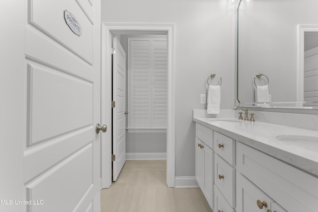 bathroom with double vanity, tile patterned flooring, baseboards, and a sink