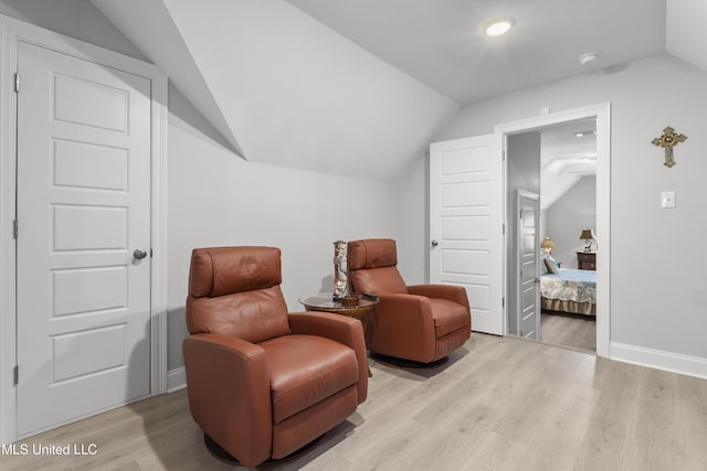 living area with light wood-type flooring, baseboards, and vaulted ceiling