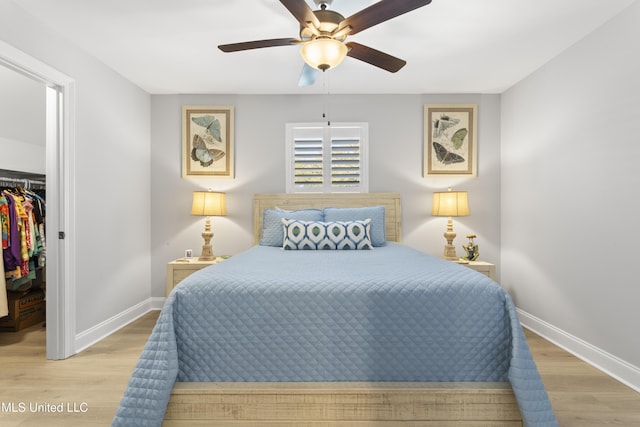 bedroom with a walk in closet, a closet, baseboards, and wood finished floors