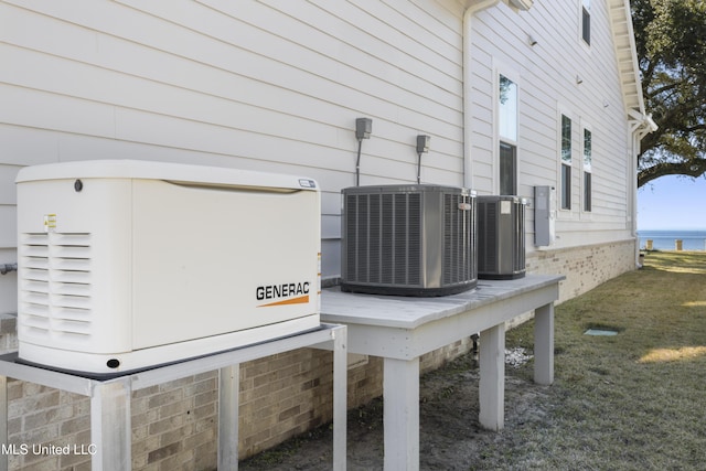 exterior details featuring central air condition unit, a water view, and a power unit