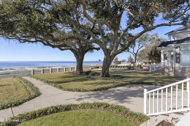 exterior space with a water view, fence, and a lawn