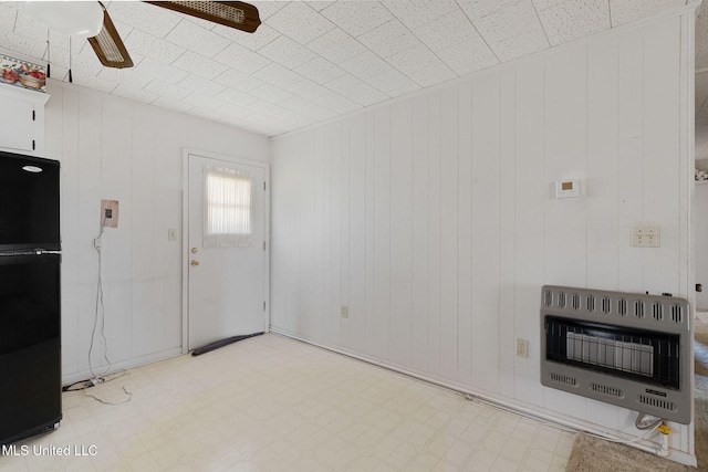 interior space featuring ceiling fan, wood walls, and heating unit