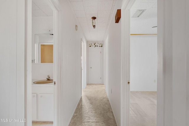 corridor featuring sink and light carpet