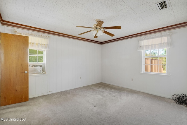 unfurnished room featuring ceiling fan, light colored carpet, crown molding, and a wealth of natural light