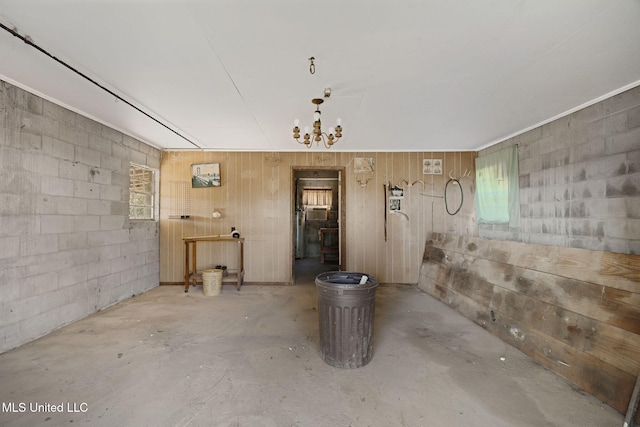 basement with a healthy amount of sunlight, wooden walls, and a chandelier