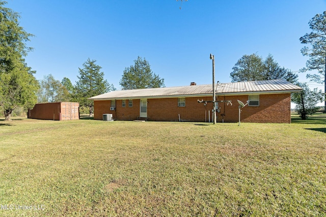 back of property featuring central AC, a yard, and a storage unit