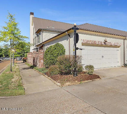 202 Eastpark St, Ridgeland, MS 39157 - view of side of home with an attached garage, concrete driveway, and a chimney