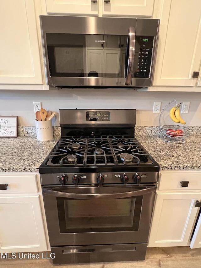 kitchen with white cabinetry, light stone countertops, and stainless steel appliances