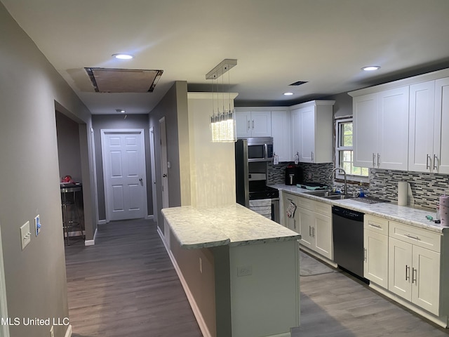 kitchen featuring appliances with stainless steel finishes, white cabinetry, hardwood / wood-style flooring, and hanging light fixtures