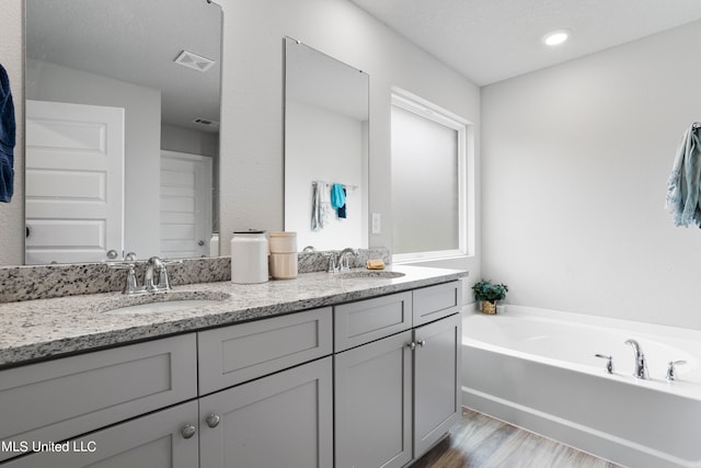 bathroom with vanity, hardwood / wood-style flooring, and a bathing tub