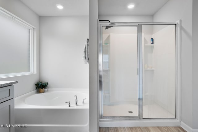 bathroom featuring vanity, separate shower and tub, and hardwood / wood-style floors