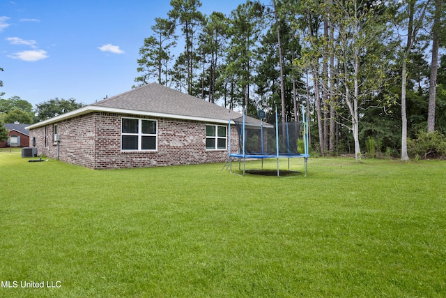 view of yard with central air condition unit and a trampoline