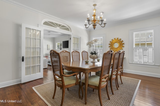 dining space featuring baseboards, ornamental molding, wood finished floors, and a notable chandelier