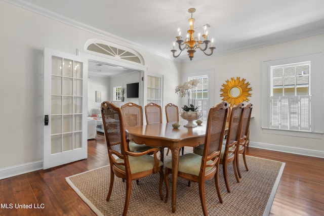 dining room with a wealth of natural light, ornamental molding, dark wood-type flooring, and an inviting chandelier