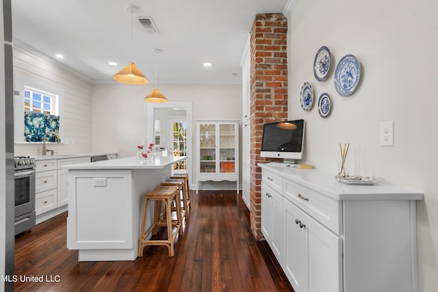 kitchen featuring white cabinets, dark hardwood / wood-style flooring, stainless steel range oven, pendant lighting, and a center island