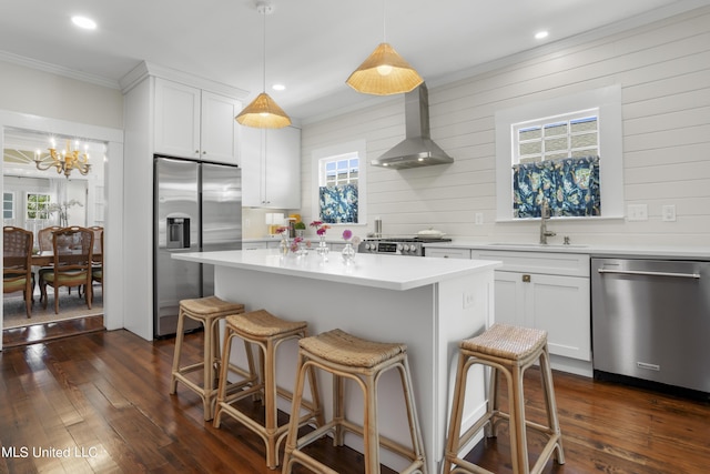 kitchen featuring appliances with stainless steel finishes, a sink, wall chimney exhaust hood, a wealth of natural light, and ornamental molding