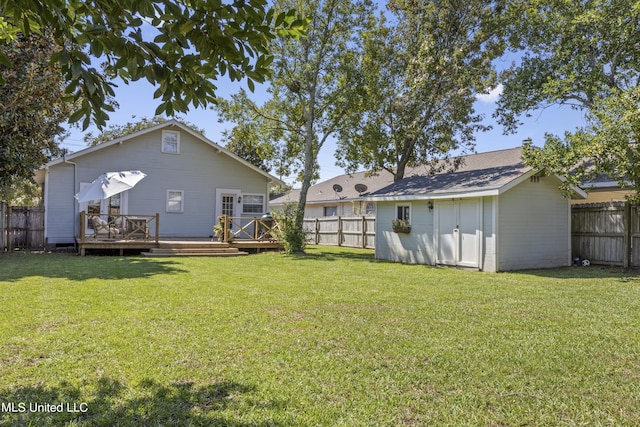 view of yard with a fenced backyard, a storage unit, a wooden deck, and an outbuilding