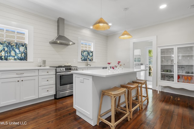 kitchen with wall chimney range hood, plenty of natural light, stainless steel range with gas cooktop, and a sink
