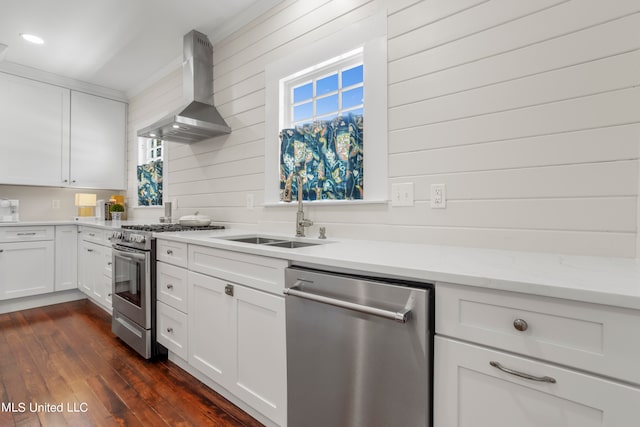 kitchen with wall chimney range hood, appliances with stainless steel finishes, white cabinetry, and dark hardwood / wood-style floors